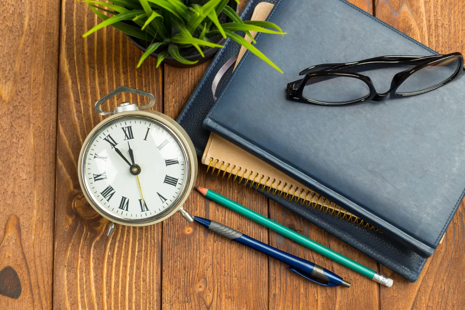 Organisation du temps de travail en entreprise représentée par un réveil et un agenda sur un bureau.