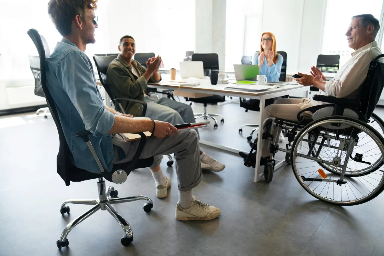 Salarié en fauteuil roulant en réunion avec ses collègues dans les bureaux d'une entreprise